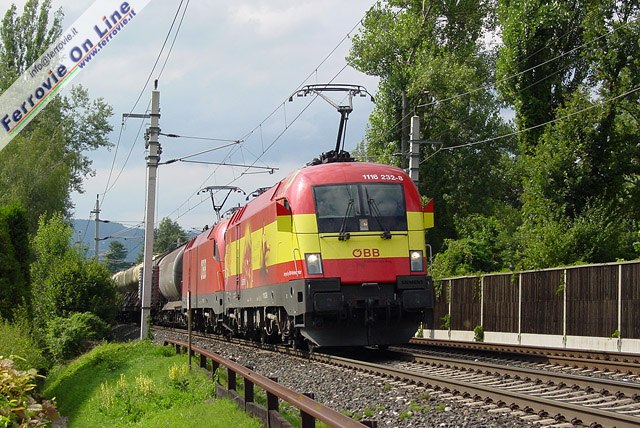 La Taurus 1116.232, in livrea "Spagna" applicata in occasione degli Europei di calcio 2008, traina insieme a un'unità gemella un convoglio merci a pochi passi dal Wörthersee, presso Pritschitz.